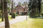 Home framed by mature shade trees and a green lawn