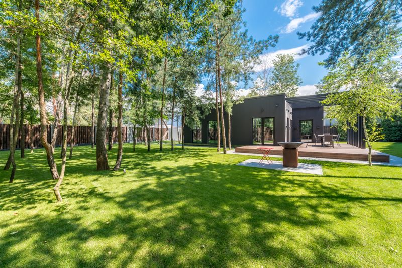 Modern home with a lawn shaded by tall trees